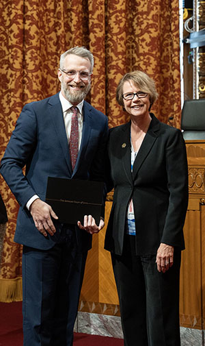 man holding a certificate standing next to a woman and smiling